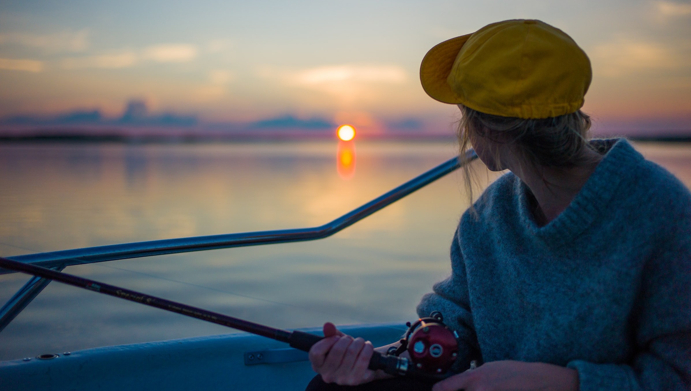 Woman fishing and facing the sunset