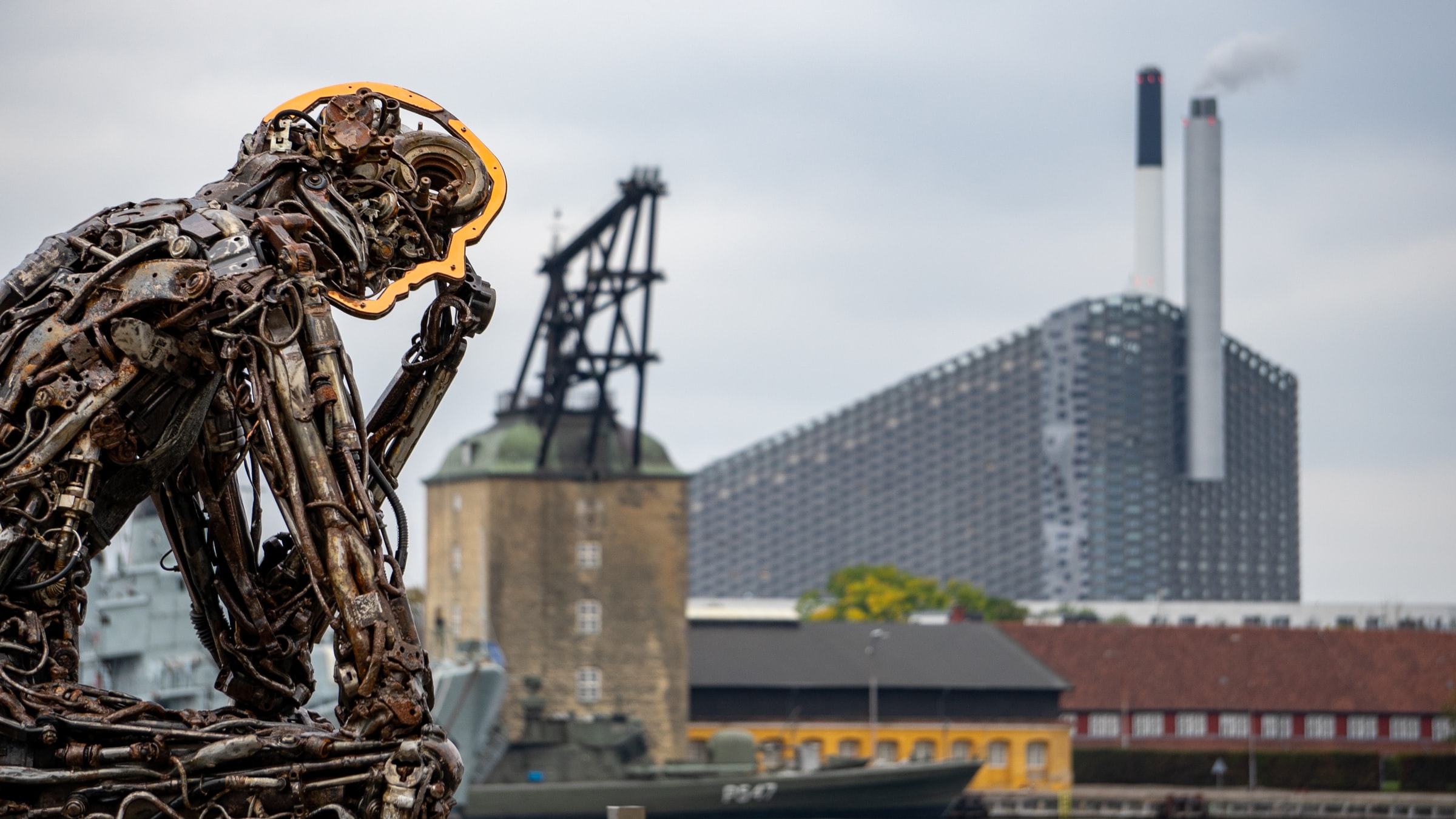 The metal sculpture of man sitting in front of the industrial area