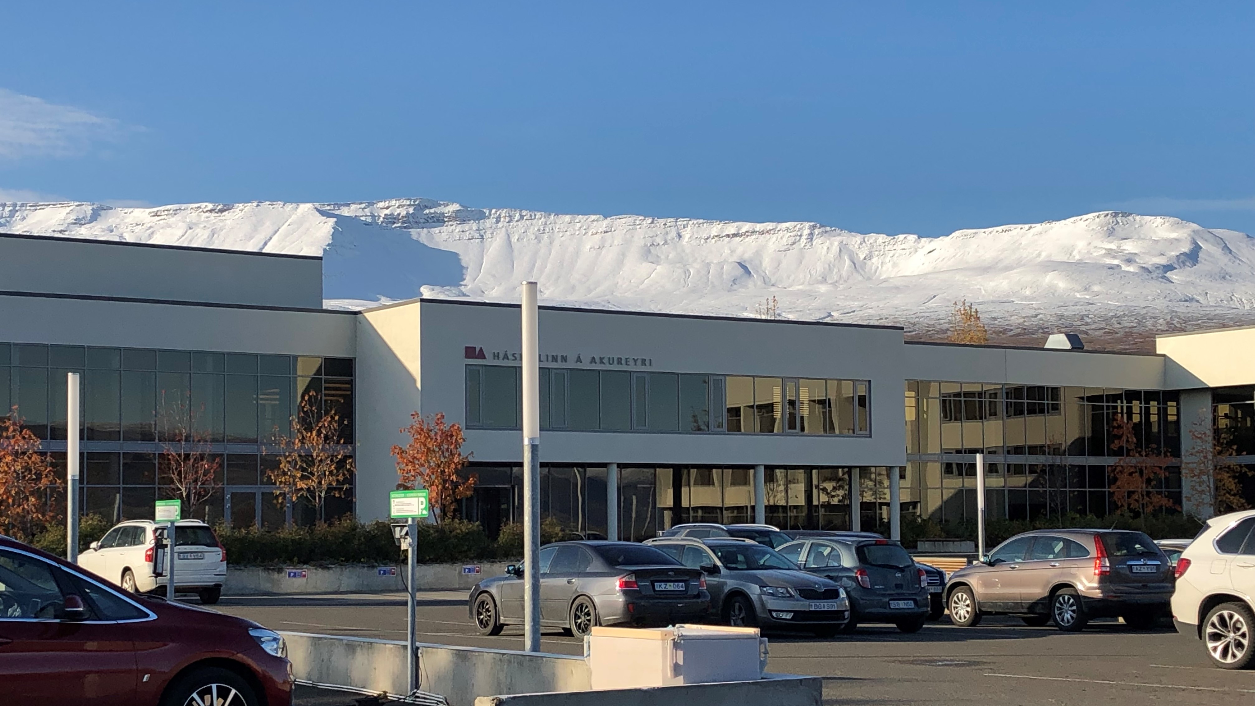 The university building, the parking lot in front of the building and the showy mountains behind the building